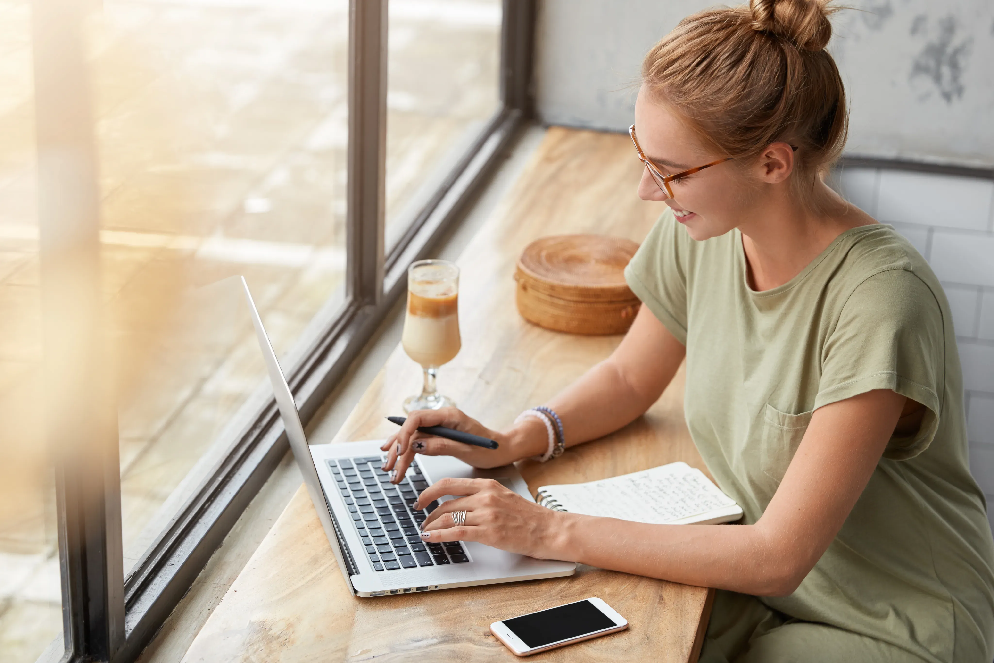 Frau arbeitet konzentriert an einem Laptop am Fenster