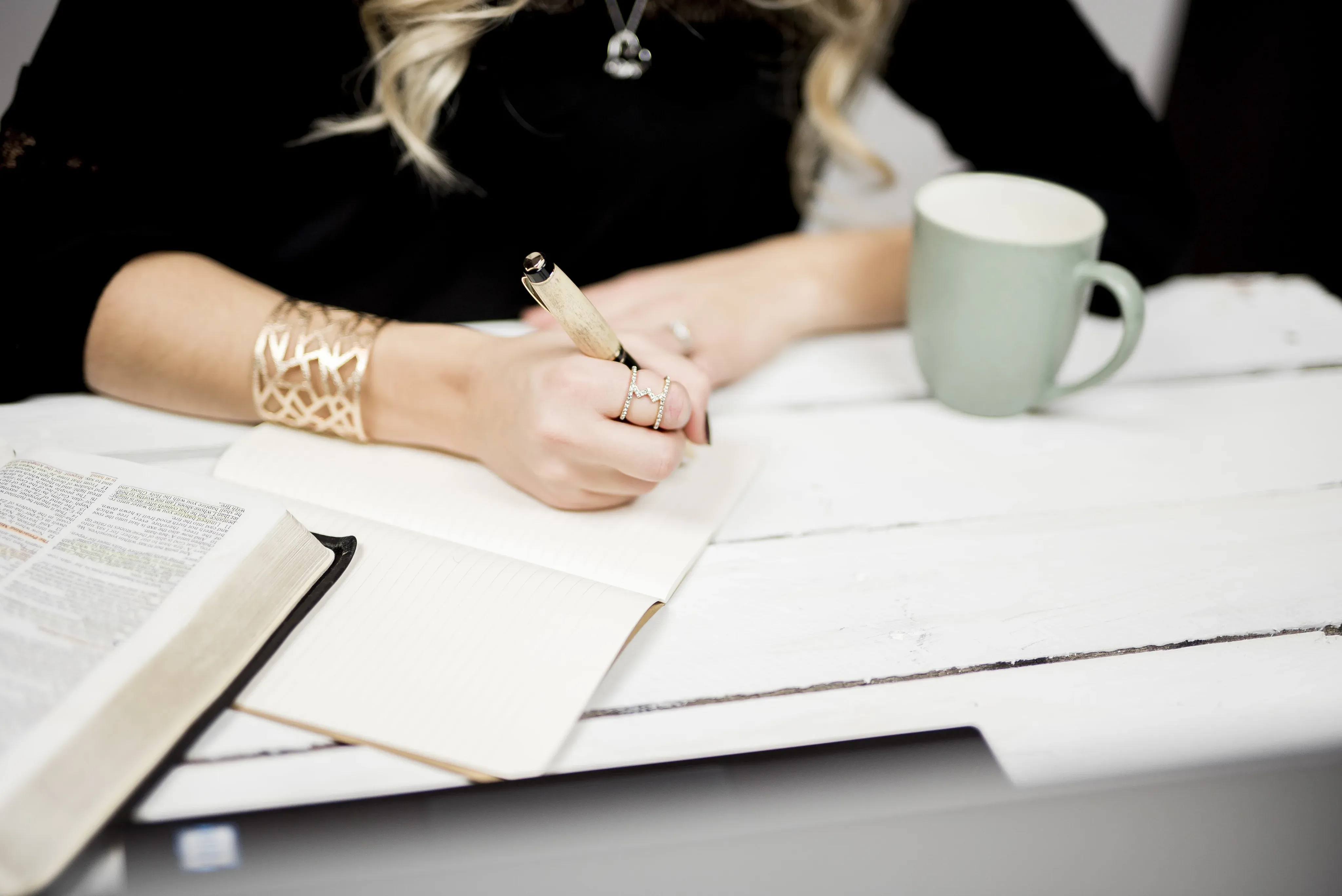 Frau schreibt handschriftliche Notizen an einem hellen Schreibtisch